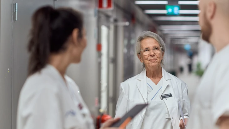 En kvinnlig läkare med två sjuksköterskor i en korridor.